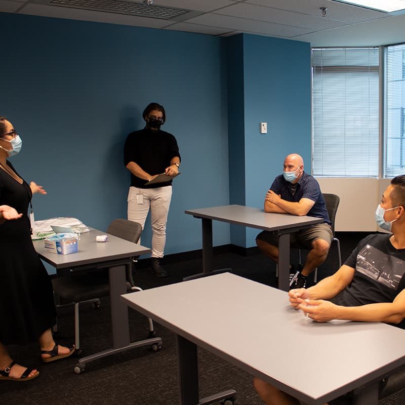 A group of people wearing masks and talking in an assessment room