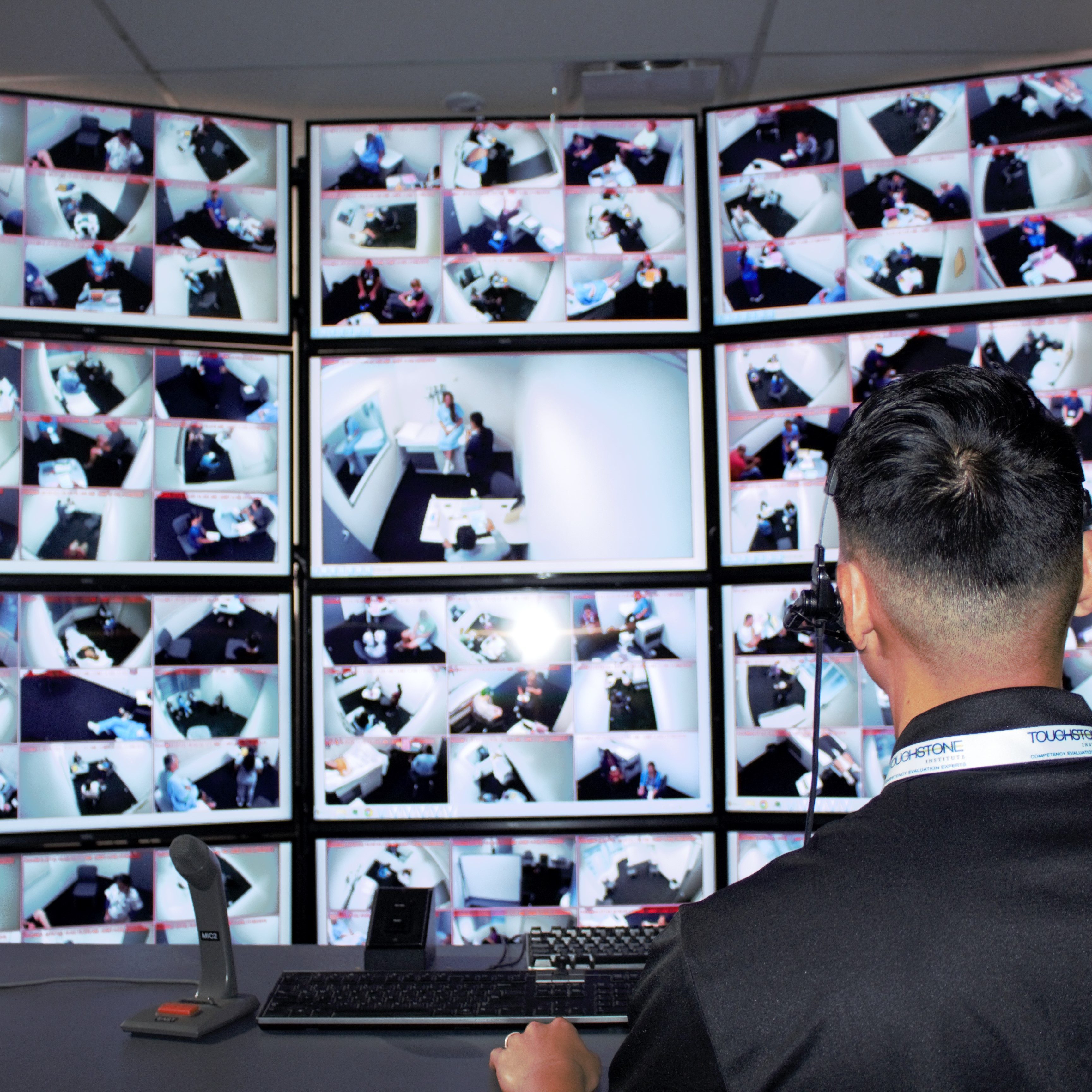 A man looking at many screens in a control room